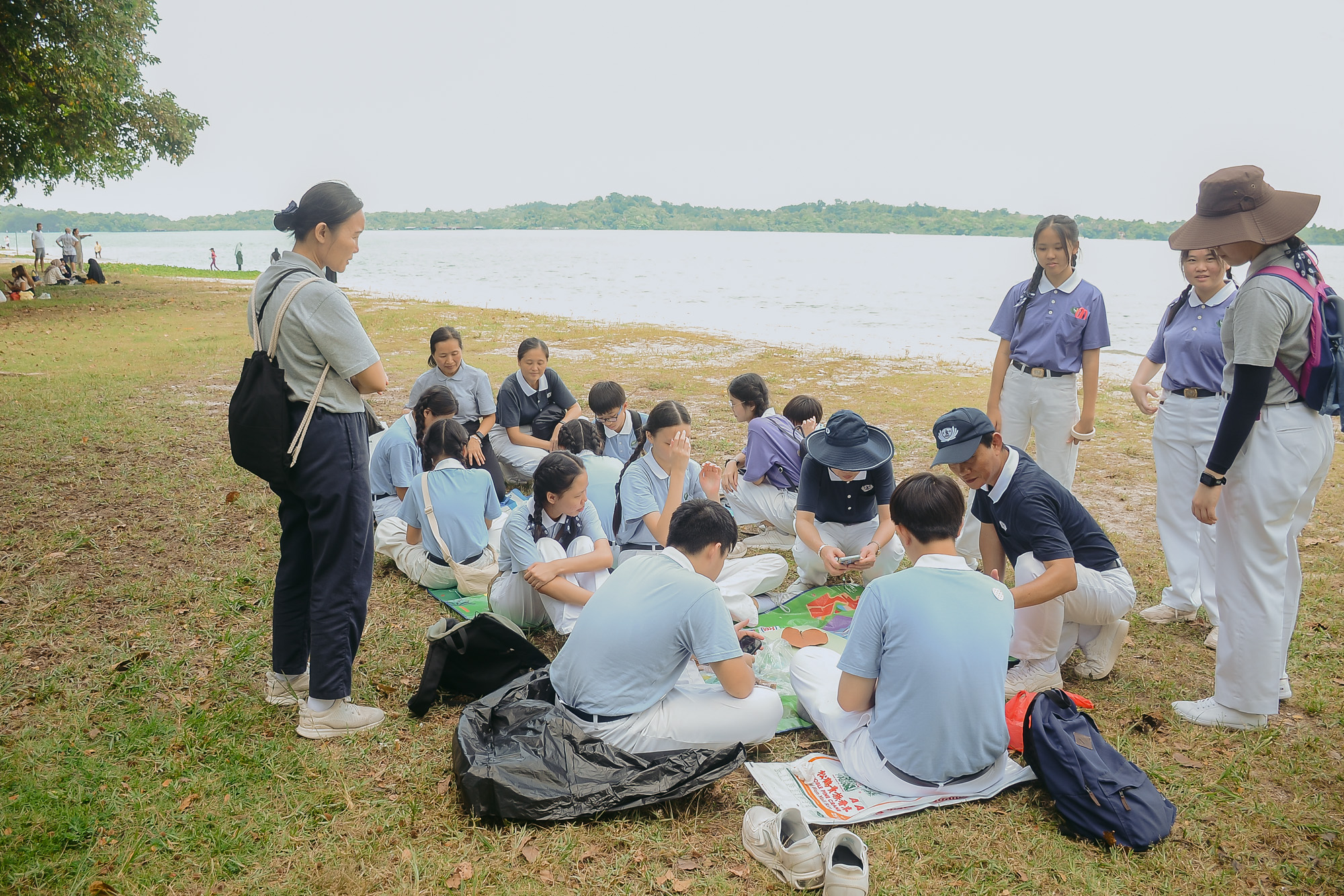队辅爸爸妈妈们把塑料席铺在草地上，方便慈少们讨论和集思广益。摄/ 蔡振加